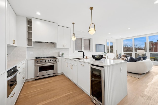 kitchen featuring appliances with stainless steel finishes, wine cooler, light wood finished floors, a peninsula, and backsplash