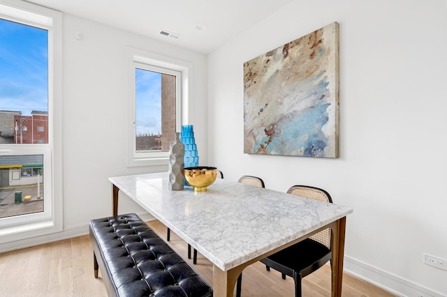 dining space with light wood-style flooring, plenty of natural light, and baseboards