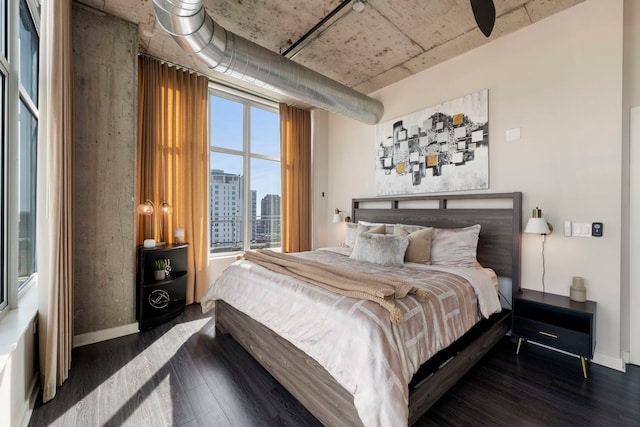bedroom with wood finished floors, baseboards, and a city view