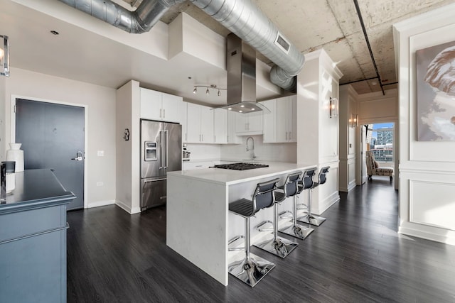 kitchen featuring high quality fridge, dark wood-type flooring, a peninsula, a kitchen bar, and light countertops