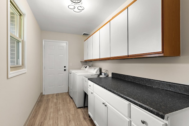 clothes washing area with washer and dryer, light wood-style flooring, and cabinet space