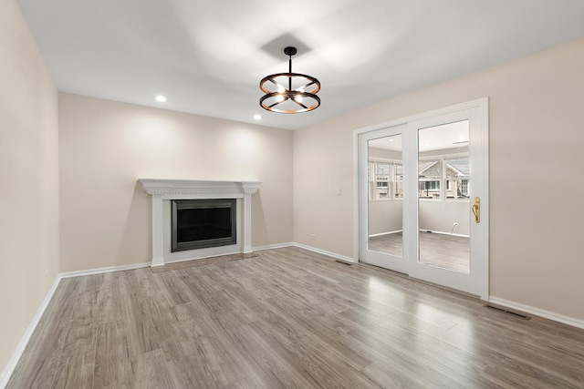 unfurnished living room featuring wood finished floors, a chandelier, baseboards, and recessed lighting