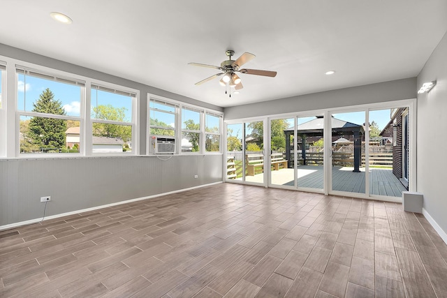 unfurnished sunroom with ceiling fan