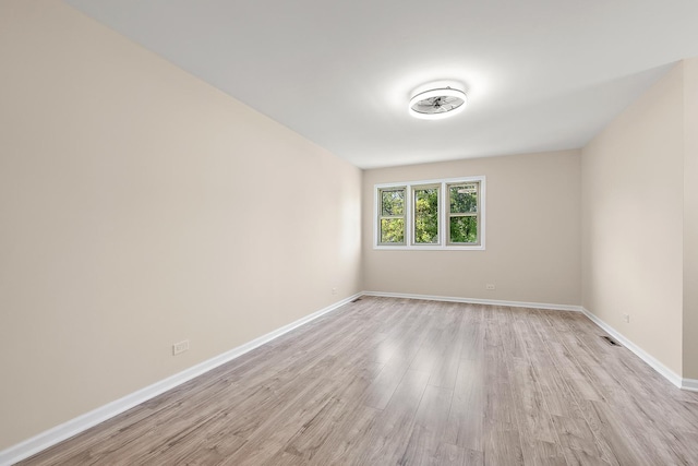 spare room featuring light wood-type flooring and baseboards