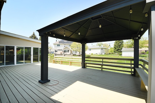 wooden deck featuring a gazebo, a lawn, and a residential view