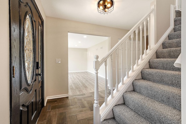foyer entrance with stairs and baseboards