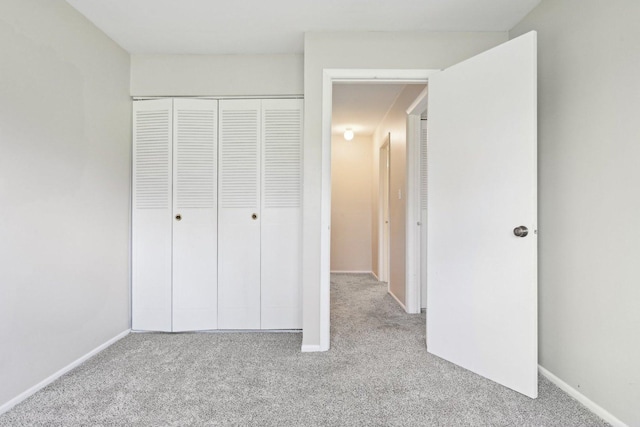 unfurnished bedroom with carpet, a closet, and baseboards