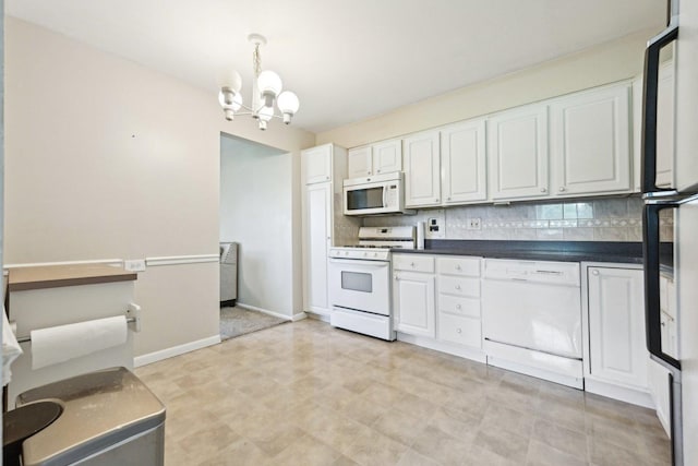 kitchen with white appliances, a chandelier, dark countertops, tasteful backsplash, and white cabinets