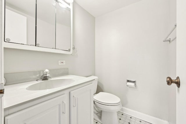 half bath featuring vanity, toilet, and baseboards