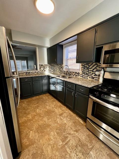 14230 S State St, Riverdale, IL 60827 - kitchen featuring appliances with stainless steel finishes, a sink, tasteful backsplash, light stone counters, and dark cabinetry