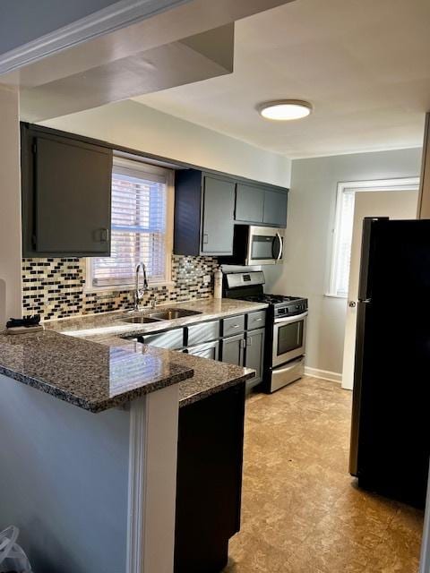 14230 S State St, Riverdale, IL 60827 - kitchen featuring stainless steel appliances, a peninsula, dark stone counters, a sink, and decorative backsplash