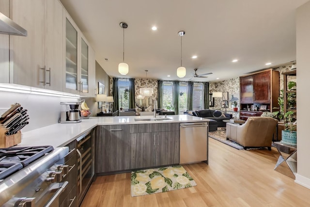 kitchen with stainless steel dishwasher, open floor plan, a sink, range, and light countertops