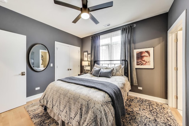 bedroom featuring light wood-type flooring, baseboards, a closet, and ceiling fan