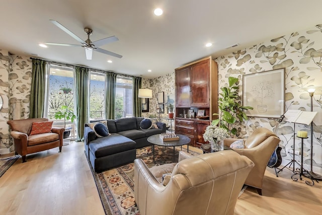 living room with a ceiling fan, light wood-type flooring, and wallpapered walls