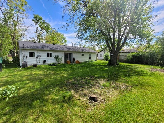 back of house with cooling unit and a lawn