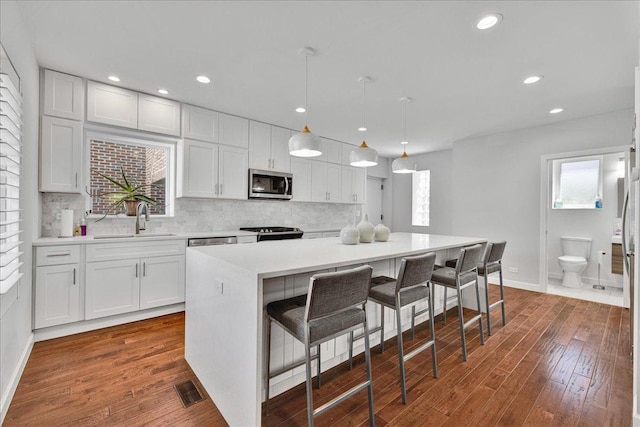 7439 W Lunt Ave, Chicago, IL 60631 - kitchen featuring stainless steel microwave, a sink, light countertops, white cabinetry, and tasteful backsplash