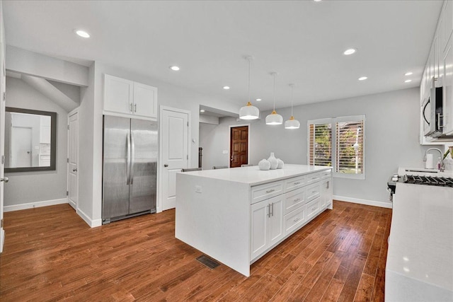 7439 W Lunt Ave, Chicago, IL 60631 - kitchen with appliances with stainless steel finishes, white cabinets, dark wood-style flooring, a center island, and light countertops