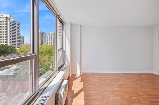 spare room with light wood-type flooring, plenty of natural light, baseboards, and a city view