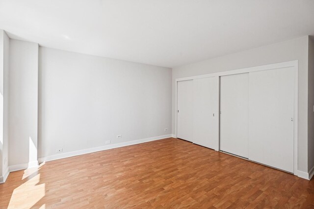 unfurnished bedroom with light wood-style flooring, baseboards, and a closet