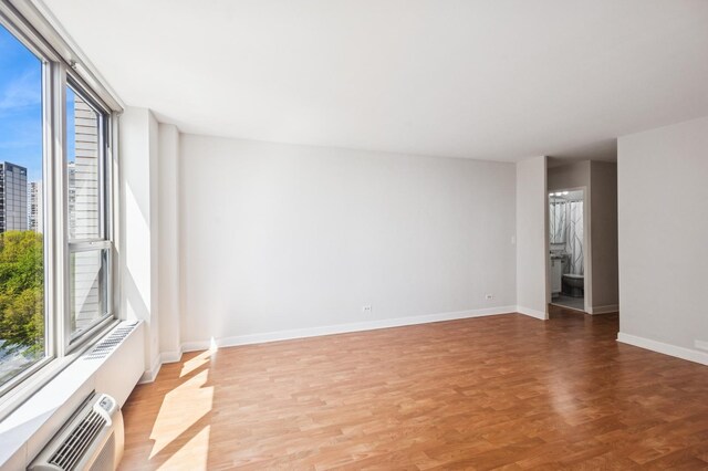 spare room with light wood finished floors, baseboards, and a wall mounted air conditioner