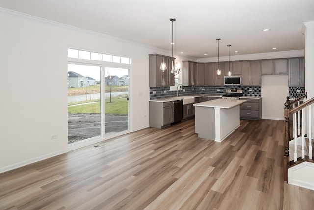 kitchen featuring stainless steel appliances, light countertops, ornamental molding, backsplash, and a water view