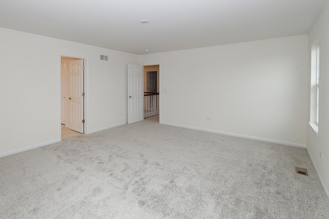 unfurnished room with light colored carpet and baseboards