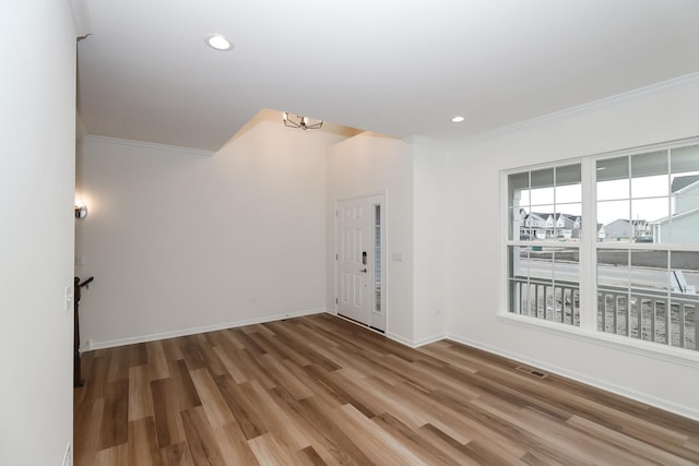 empty room with ornamental molding, a chandelier, wood finished floors, baseboards, and recessed lighting