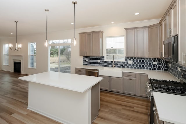 kitchen with stainless steel appliances, a sink, decorative backsplash, light wood-style floors, and crown molding