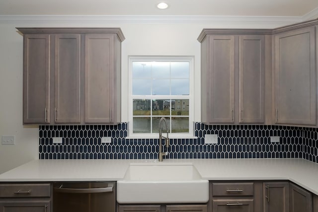 kitchen with a sink, dishwasher, decorative backsplash, light countertops, and ornamental molding