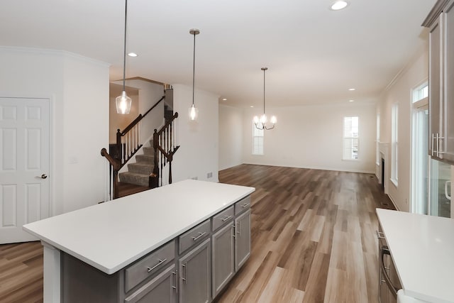 kitchen featuring gray cabinets, recessed lighting, light countertops, a center island, and ornamental molding