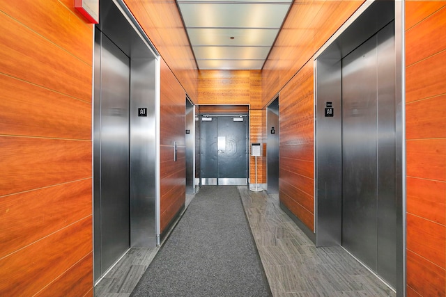 hallway with elevator and wooden walls
