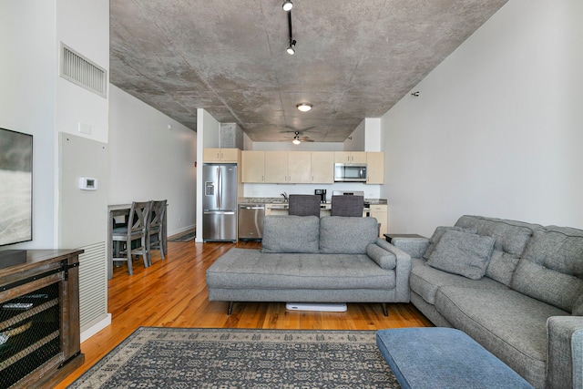 living area with light wood-type flooring, ceiling fan, and baseboards