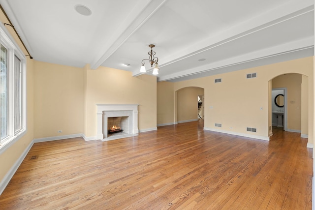 1161 Gavin Ct, Lake Forest, IL 60045 - unfurnished living room featuring arched walkways, beamed ceiling, light wood-type flooring, a fireplace with flush hearth, and healthy amount of natural light