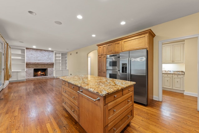 1161 Gavin Ct, Lake Forest, IL 60045 - kitchen with stainless steel appliances, wood finished floors, light stone counters, arched walkways, and a kitchen island