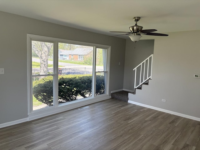 unfurnished room with dark wood-type flooring, baseboards, and stairs