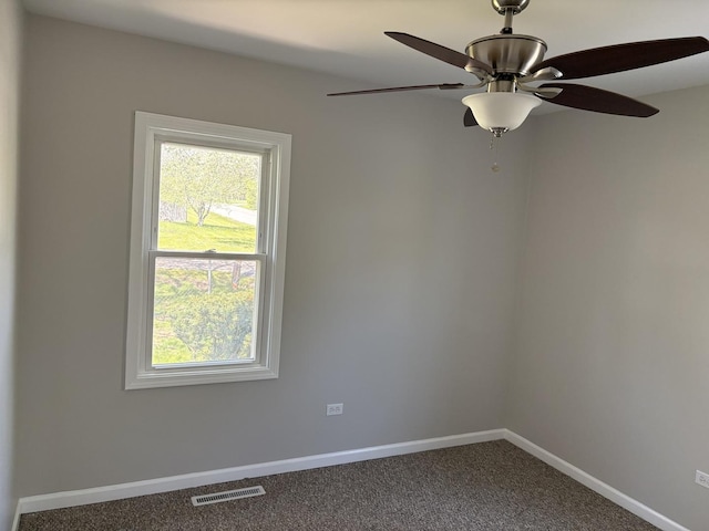 empty room with dark carpet, baseboards, healthy amount of natural light, and ceiling fan