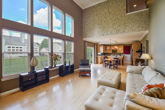 24706 Apollo Dr, Plainfield, IL 60585 - living room with ornamental molding, a high ceiling, light wood-style floors, a chandelier, and baseboards