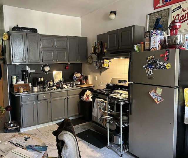 kitchen with freestanding refrigerator, range with gas stovetop, ventilation hood, tasteful backsplash, and light tile patterned flooring