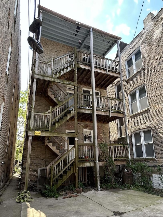 rear view of house with stairs and brick siding
