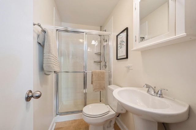 bathroom featuring a stall shower, toilet, a sink, and baseboards