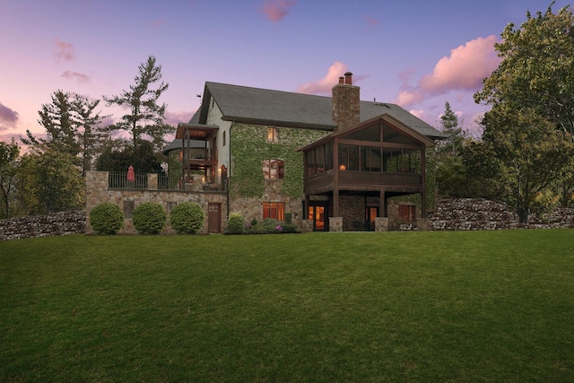 236 Steeplechase Rd, Barrington Hills, IL 60010 - back of property at dusk with stone siding, a balcony, a yard, a chimney, and a sunroom