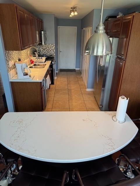 3245 Bremerton Ln, Aurora, IL 60504 - kitchen with stainless steel appliances, decorative backsplash, light countertops, a sink, and light tile patterned floors