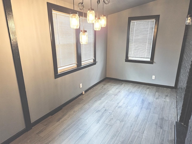 empty room featuring wood finished floors, a chandelier, and baseboards