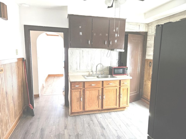 kitchen with a sink, freestanding refrigerator, light wood-type flooring, and light countertops