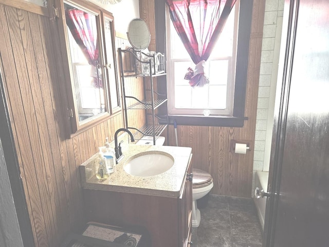 bathroom with wood walls, toilet, and vanity