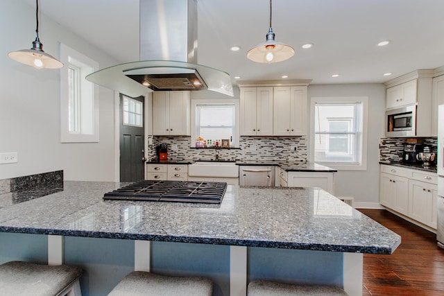 5236 N Mobile Ave, Chicago, IL 60630 - kitchen featuring island range hood, stainless steel appliances, a sink, a peninsula, and a breakfast bar area