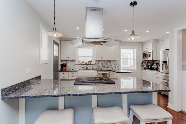5236 N Mobile Ave, Chicago, IL 60630 - kitchen with island exhaust hood, appliances with stainless steel finishes, a sink, decorative backsplash, and a peninsula