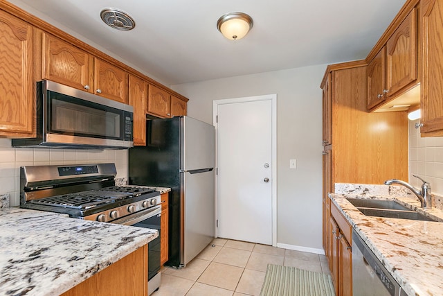kitchen featuring stainless steel appliances, a sink, decorative backsplash, and light tile patterned flooring