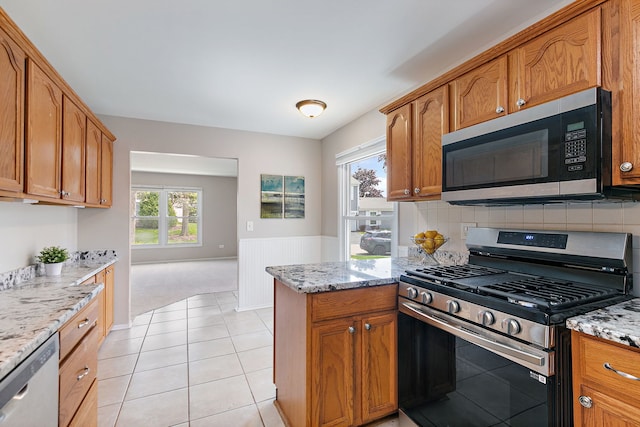 kitchen with appliances with stainless steel finishes, light stone countertops, and brown cabinetry
