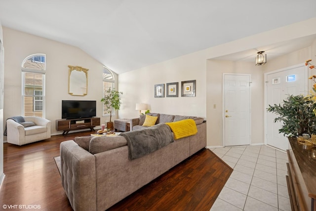 living room featuring lofted ceiling, wood finished floors, and baseboards